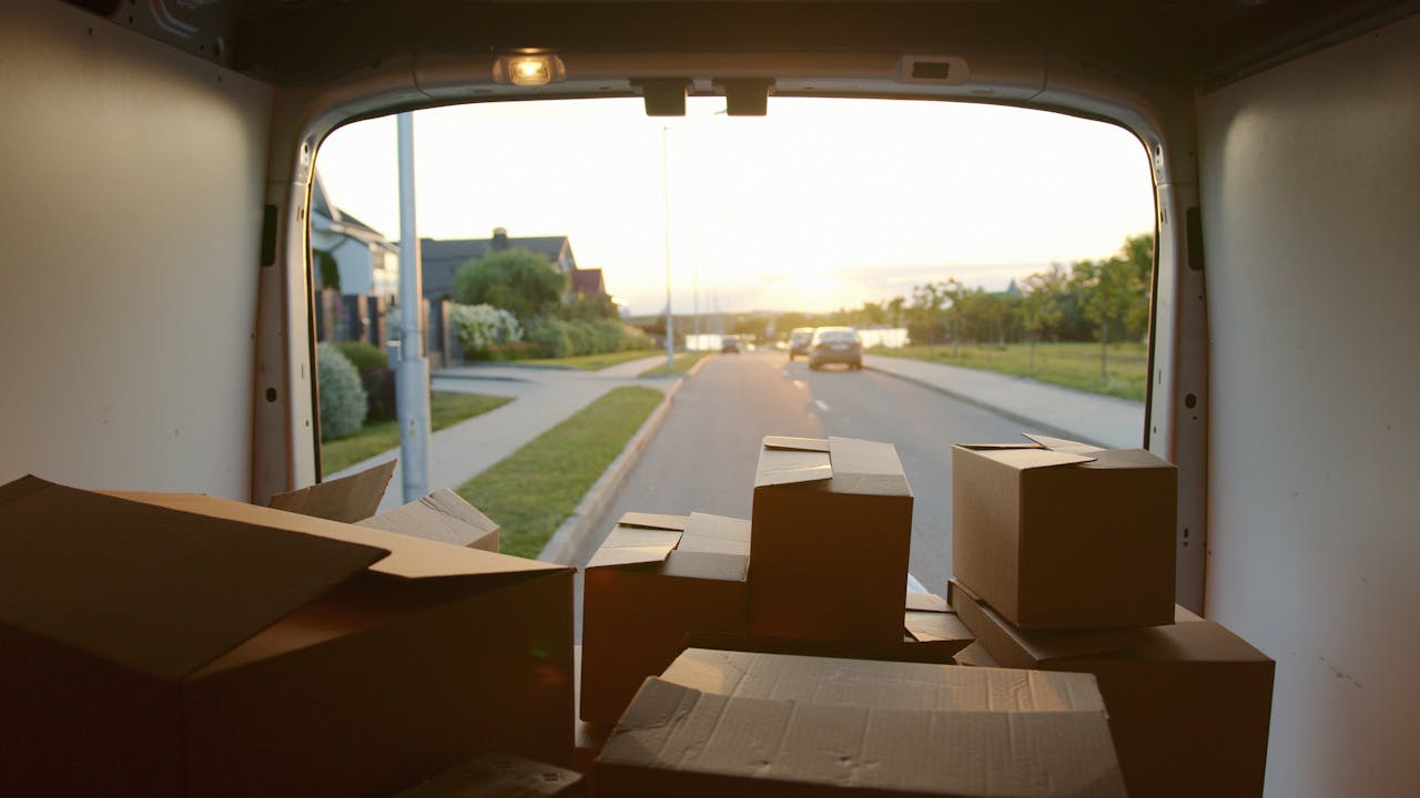 our-services-3 A scenic view from a delivery van loaded with cardboard boxes at sunset on a suburban street.
