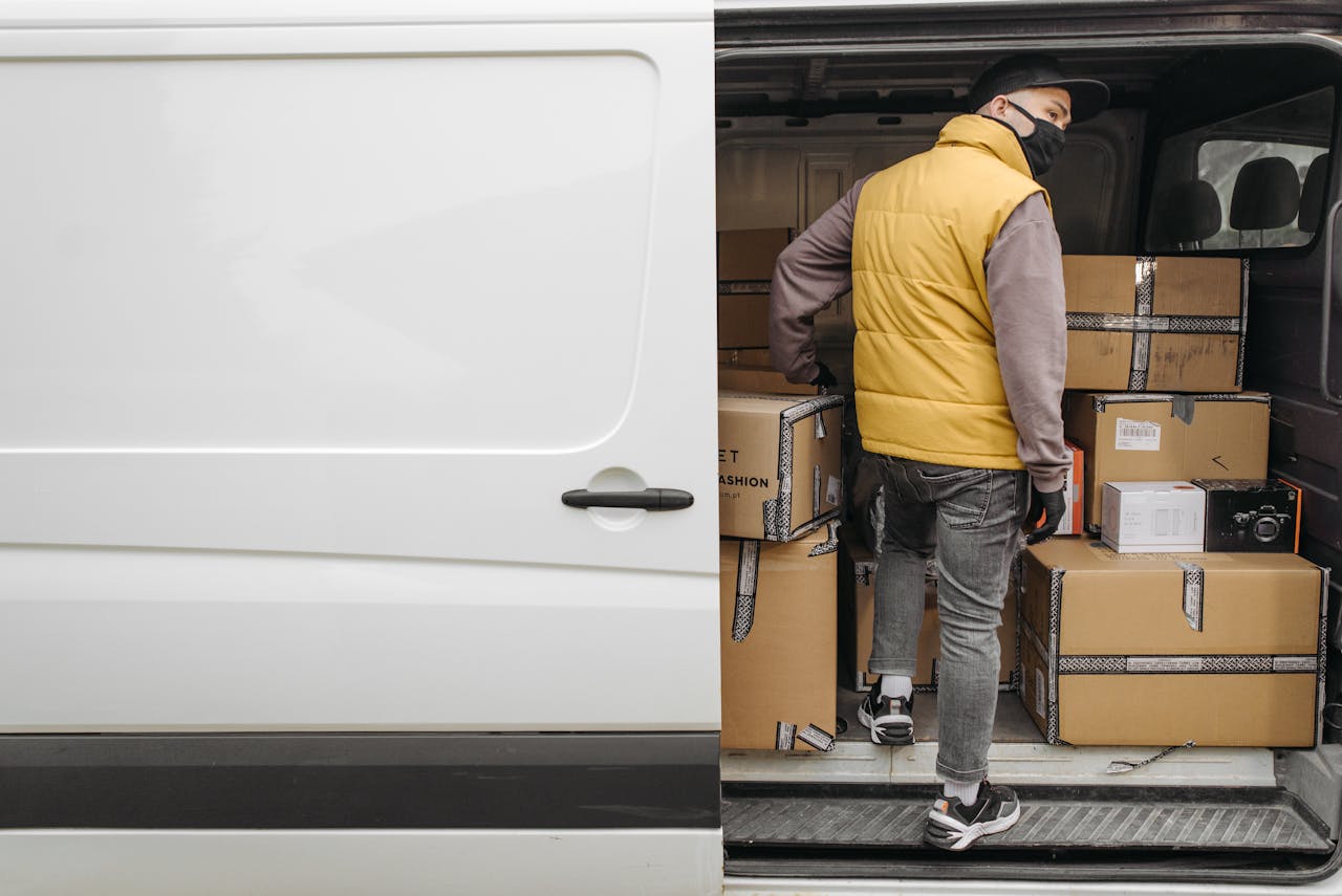 gallery-5 A deliveryman unloading packages from a van, showcasing modern logistics.