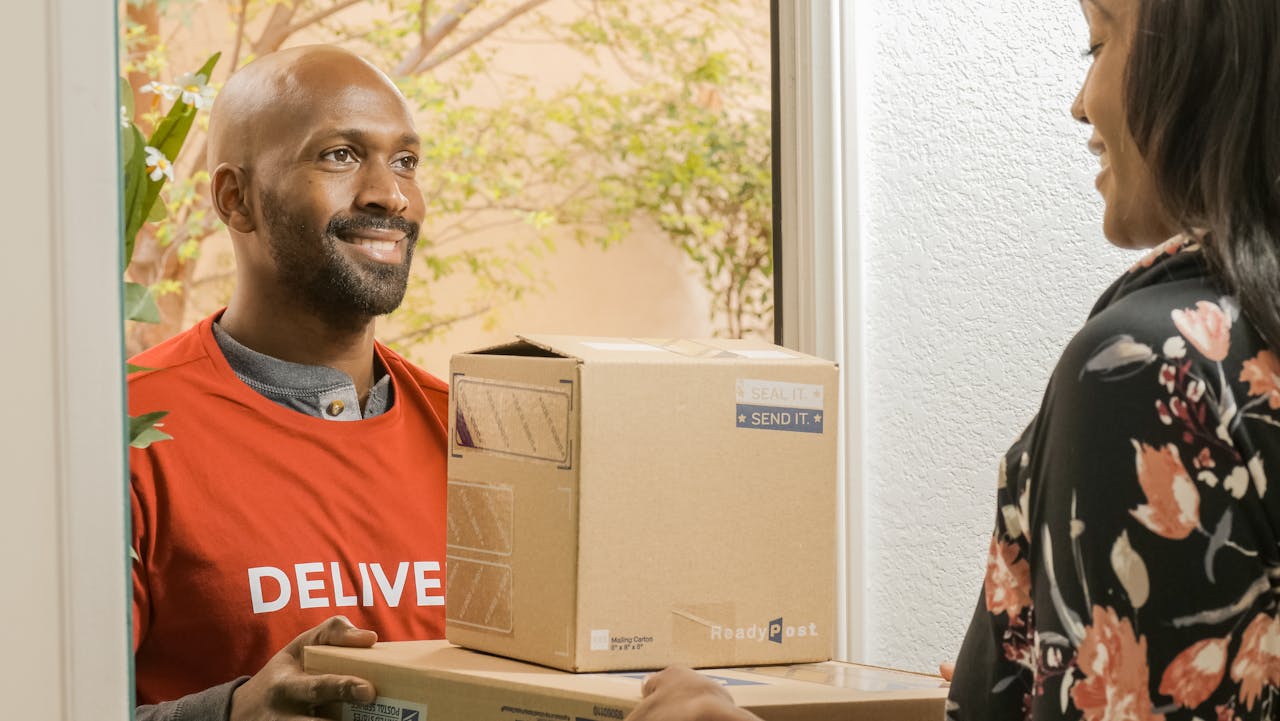 A delivery person handing packages to a smiling recipient at the door.