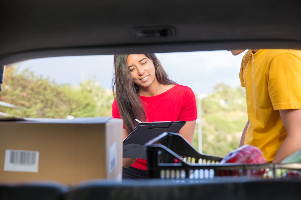 Smiling woman delivers packages from a car outdoors, enhancing customer experience.